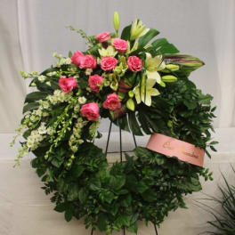 Pink roses and white lilies arranged in a large standing wreath