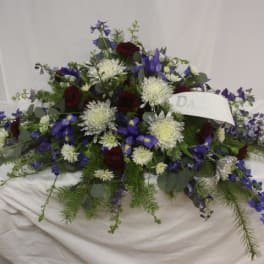 Casket spray with blue, white, and burgundy flowers