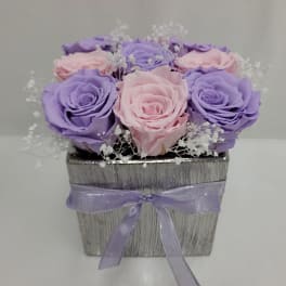 Pink and lavender roses in a silver square box with a purple ribbon