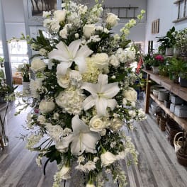 Large white floral standing spray with lilies, roses, and hydrangeas