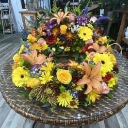 Large colorful floral wreath with lilies, roses, and daisies on a round table
