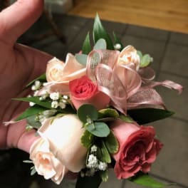 Small hand-tied bouquet of pink and cream roses with ribbon