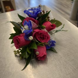 Small bouquet of pink roses and blue flowers with decorative accents