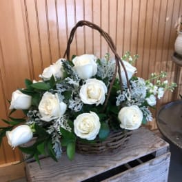 White roses in a wicker basket with greenery
