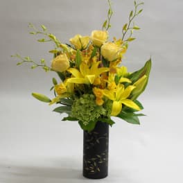 Yellow roses and lilies arranged in a black vase