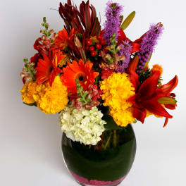 Bright mixed bouquet in a glass vase with red, orange, yellow, purple, and white blooms