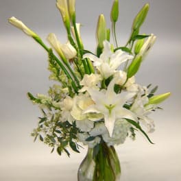 White lilies and calla lilies in a clear glass vase