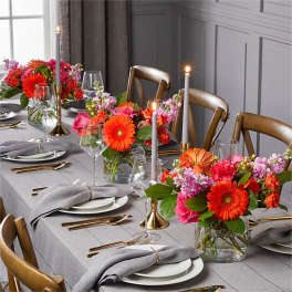 Bright mixed flower centerpieces on a set dining table with candles