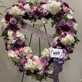 Heart-shaped floral wreath with purple, pink, and white flowers on an easel