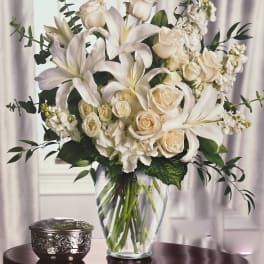 White lilies and cream roses in a clear glass vase