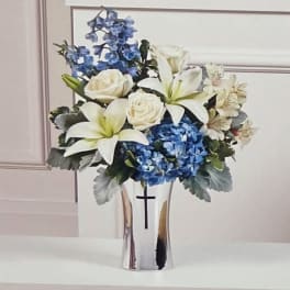 White lilies and roses with blue hydrangeas in a silver vase