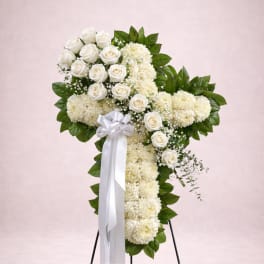 White rose and chrysanthemum cross on a stand with a white ribbon