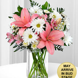 Pink lilies and white daisies arranged in a clear glass vase