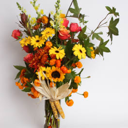 Tall autumn bouquet in a clear glass vase with yellow and orange flowers