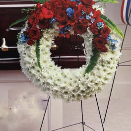 Circular funeral wreath of red roses and white flowers on a stand