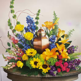 Colorful floral arrangement around a copper urn with yellow roses and lilies