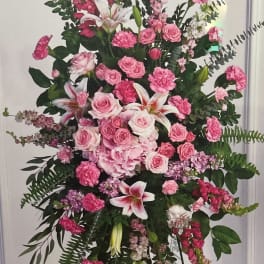 Tall pink floral standing spray with roses, lilies, and carnations on an easel