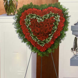 Heart-shaped red rose wreath on a stand