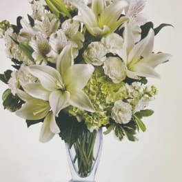 White lilies and green hydrangeas in a clear glass vase