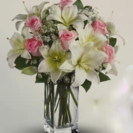Pink roses and white lilies in a clear glass vase