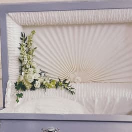 White floral spray on a white casket with green accents