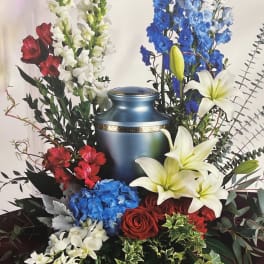 Funeral urn surrounded by red, white, and blue flowers