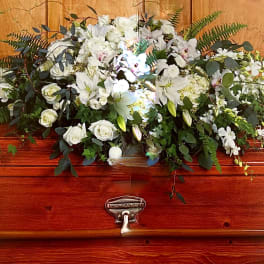White floral spray on a polished wooden casket