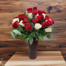 Bouquet of red and white roses in a tall dark vase