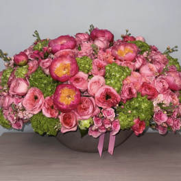 Pink floral arrangement with roses and peonies in a low bowl