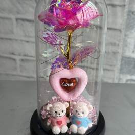 Pink iridescent artificial rose under a glass dome with two teddy bears