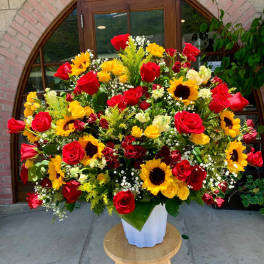 Large bouquet of red roses and yellow sunflowers in a white vase