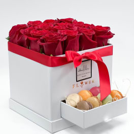 Red roses in a white gift box with a drawer of macarons
