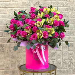 Large bouquet of pink roses and yellow orchids in a pink hat box