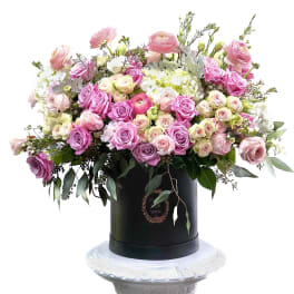 Large pink and white rose arrangement in a black hatbox