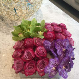 Pink roses and purple orchids arranged in a square box