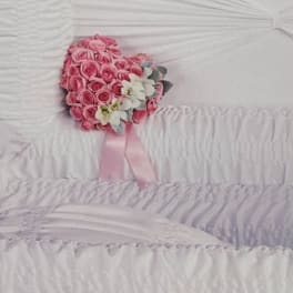 Pink rose bouquet with white flowers and a pink ribbon on a white casket