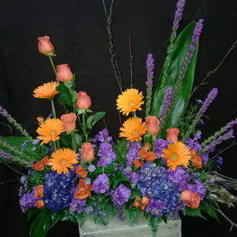 Colorful floral arrangement with orange daisies, pink roses, and purple blooms