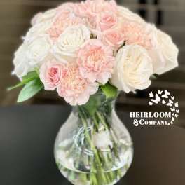Pink and white roses with carnations in a clear glass vase
