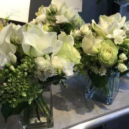White and pale green floral arrangements in square glass vases