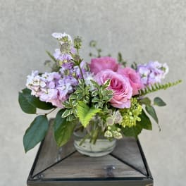 Pink roses and lavender flowers arranged in a glass vase