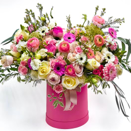 Mixed pink and white flowers in a bright pink hatbox