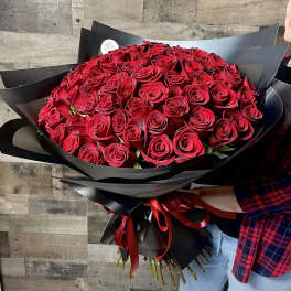 Large bouquet of red roses wrapped in black paper with a red ribbon