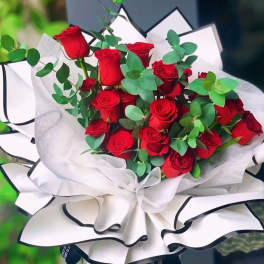 Bouquet of red roses wrapped in white paper with black trim