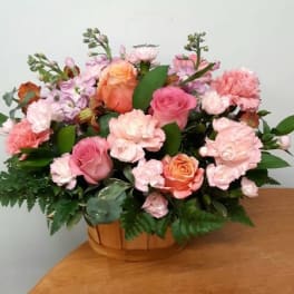 Pink and peach rose bouquet with carnations in a wooden basket