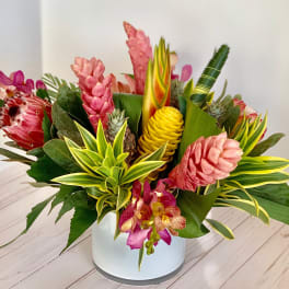 Tropical flower arrangement in a white vase with pink and yellow blooms