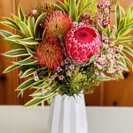 Tropical bouquet with pink protea in a white vase