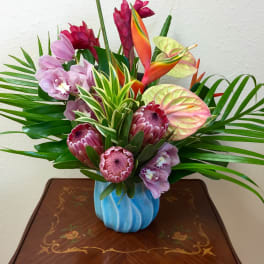 Tropical bouquet with orchids, protea, and anthuriums in a blue vase