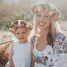 Woman and child wearing floral crowns and white dresses outdoors