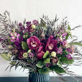 Purple orchid and rose arrangement in a blue vase
