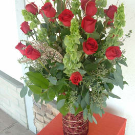 Tall bouquet of red roses with green filler in a decorative vase